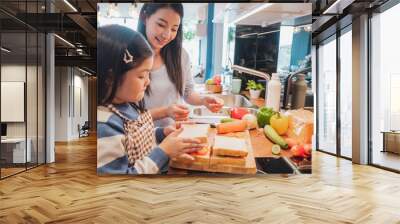 Asian Mother and her daughter kid cooking food for breakfast in kitchen Wall mural