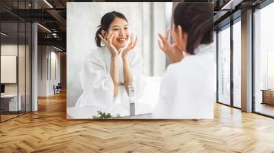 Asian woman cleaning face front of mirror, skin care and cosmetic removal concept Wall mural