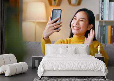 Asian woman making video call via mobile phone talking with friends Wall mural