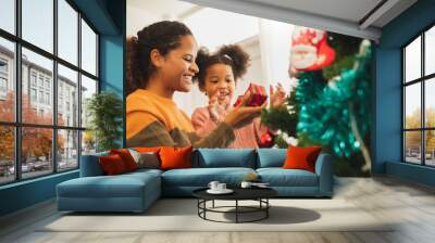 Black african mother and her cute daughter decorating christmas tree for christmas and happy new concept Wall mural