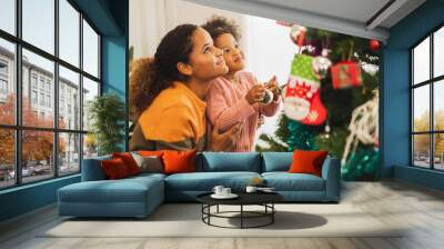 Black african mother and her cute daughter decorating christmas tree for christmas and happy new concept Wall mural