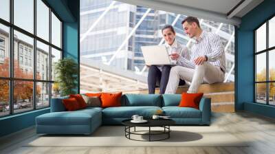 Businessman and businesswoman talking during working online on laptop at outdoor office Wall mural