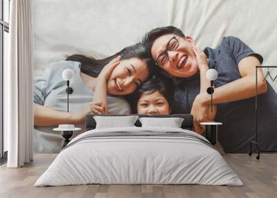 Happy Asian family laying on bed in bedroom with happy and smile, top view Wall mural