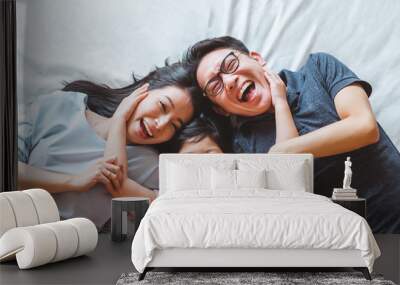 Happy Asian family laying on bed smile, top view Wall mural