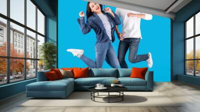 Young Asian couple man and woman jumping with happy and fun over blue background Wall mural