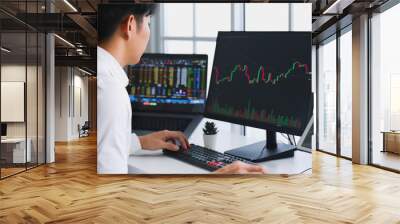 Young Asian investor watching the change of stock market on computer laptop screen. Wall mural