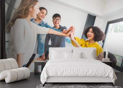 Young Asian people stacking hands for teamwork concept Wall mural