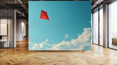 Red kite flying in a clear blue sky with scattered clouds on a sunny day, representing freedom and joy in nature. Wall mural