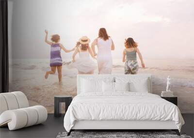 Summer of Happy girls running together on sunset sea beach. Holiday concept. Cinema film tone with grain. Wall mural