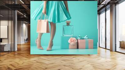 Eyecatching shopping bag concept featuring a woman in a trendy dress and shoes, with a perfume and gift box, set against a light pastel blue background Wall mural