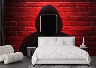 Mysterious figure in a hoodie, standing against a red brick wall. Wall mural