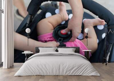 Action of mother hand is fastening and locking belt of baby cart seat. Transportation with safety and equipment object concept photo. Selective focus. Wall mural