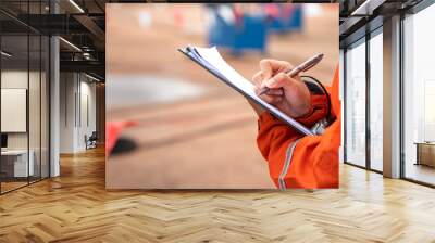 Action of safety officer is writing and check on checklist document during safety audit and inspection at drilling site operation. Industrial expertise occupation working scene. Wall mural