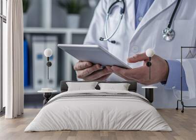 Medical office with a doctor reviewing patient files on a tablet with a well-organized workspace in the background Wall mural