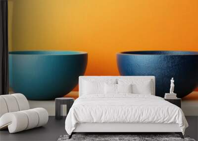 Two textured ceramic bowls in blue and teal, positioned on a light surface against a vibrant orange backdrop. Wall mural