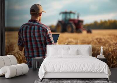 a man farmer with tablet in his hand in harvest field and machine background Wall mural