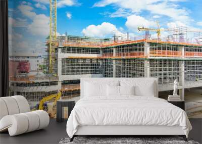 Construction site and unfinished high-rise building with scaffolding, Yellow tower crane and blue sky cloudy. Wall mural