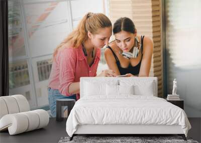 Two beautiful young women playing phone and tablet. concept of relaxation. Wall mural