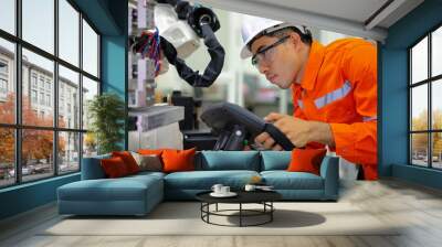 Smart factort concept: An engineer use handheld controller setting industrial robot in productionplant. Wall mural