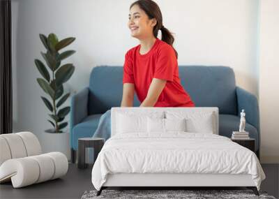 A beautiful woman in a red shirt sitting on the sofa happy smile. Wall mural