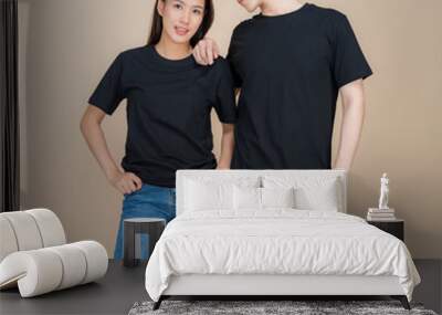 An image of a male and female fashion model standing in black t-shirt and jeans standing in studio on beige background Wall mural