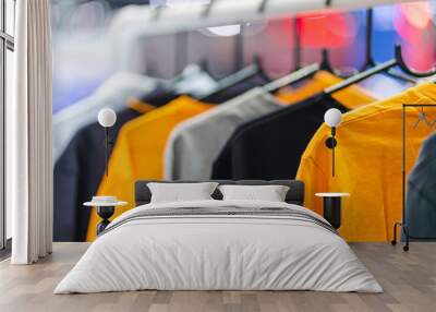 Close up of t-shirts on hangers, apparel background Wall mural