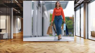 Outdoors portrait of Happy woman holding shopping bags Wall mural