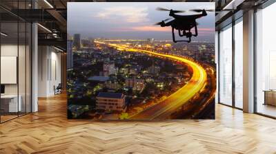 Silhouette of drone flying above city at sunset Wall mural