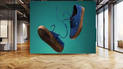 Close up view of levitation blue sneakers shoes with  flying laces over green background with copy space for text.  Wall mural