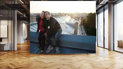 man and woman siting on rooftops historic center St. Petersburg and enjoying with  amazing sunset. Wall mural