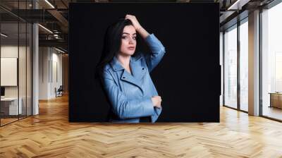 Portrait brunette woman on black background. Young woman in a blue leather jacket. Wall mural