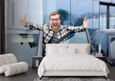 Great Car. Cheerful guy standing near auto, gesturing thumbs up buying vehicle in dealership center Wall mural