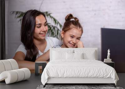 A young mother with little daughter are shopping on the Internet at personal computer Wall mural