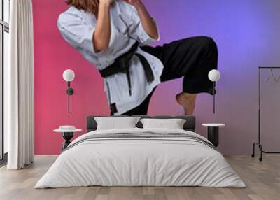 Athletic woman in traditional kimono is practicing karate in studio. Wall mural