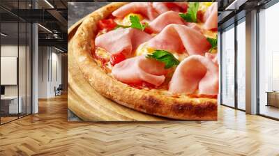 Closeup of pizza with melted mozzarella, ham, quail eggs, tomatoes and fresh greens on wooden board Wall mural