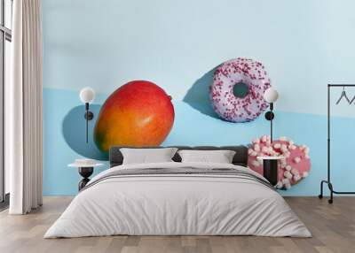 Composition of fresh fruits and sweets, two donuts and juicy mango Wall mural