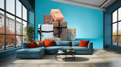 Different sizes, colorful, striped and plain paper gift boxes tied with ribbons and bows on a blue surface and background. Close-up, copy space. Wall mural