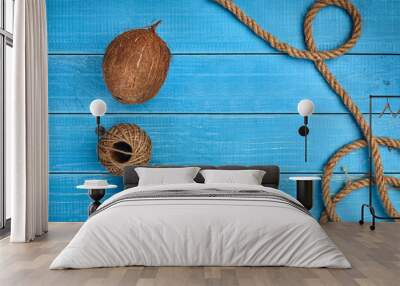 Ripe coconut, two skeins of jute twine or thread and a rope on blue wooden background or desktop. Close up, copy space Wall mural