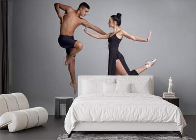 Two athletic modern ballet dancers are posing against a gray studio background. Wall mural