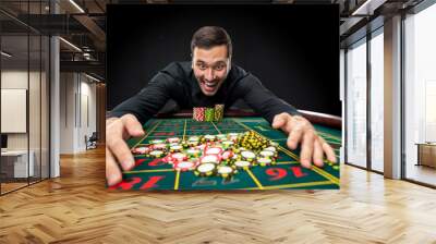 Young handsome man playing roulette wins at the casino Wall mural