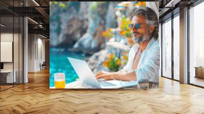 Adult man working on a laptop in a cafe on the resort coast Wall mural