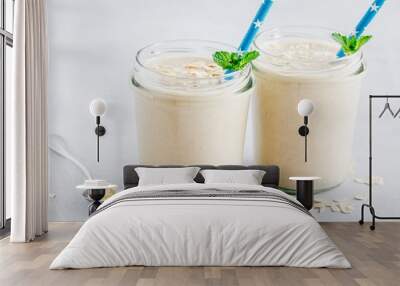 Banana oats smoothie or milkshake in glass mason jars on a stone background Wall mural