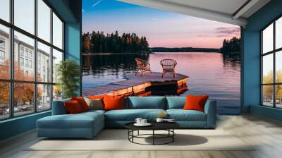 Two wooden chairs on a wood pier overlooking a lake at sunset Wall mural