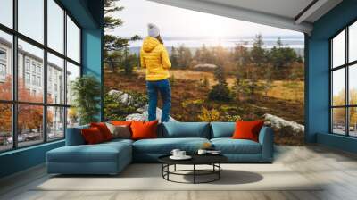 Woman traveler in yellow jacket from back hike in autumn forest in Finland Lapland. Wall mural