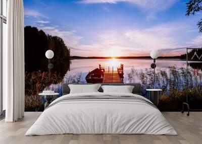 Wooden pier with fishing boat at sunset on a lake in Finland Wall mural