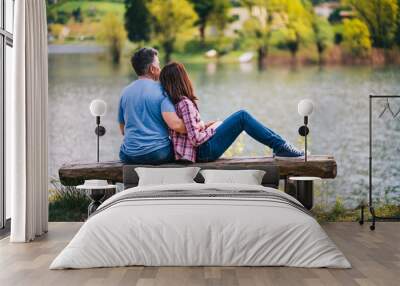 Young couple sitting on bench under a tree at lake in Italy. Wall mural