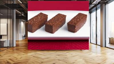 Three brown raw vegan bars on white plate and red background Wall mural