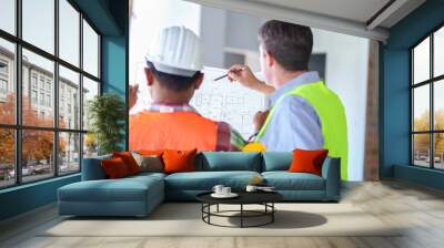 Two construction engineers holding blue print and inspecting the construction site Wall mural