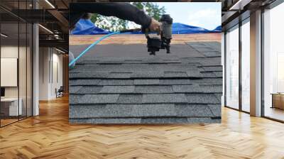 handyman using nail gun to install shingle to repair roof Wall mural