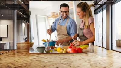 Attractive couple is cooking together organic healthy food in kitchen. Wall mural